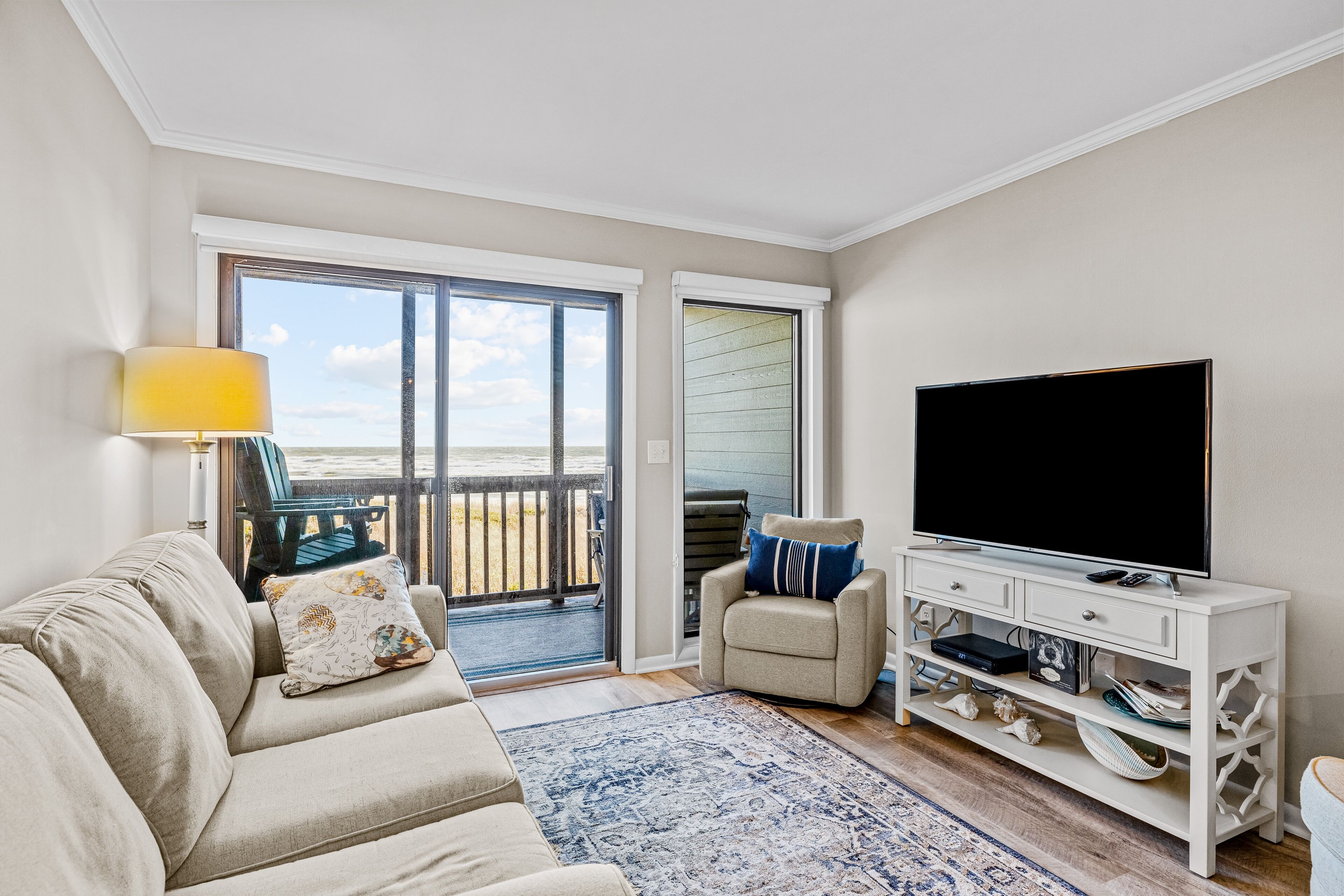 A living room with a sofa, a television, a coffee table, and a view of the outdoors.