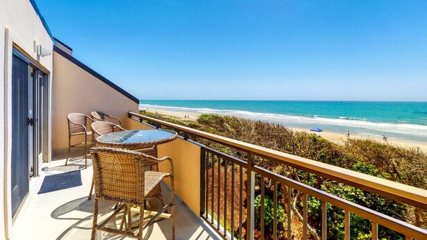 A balcony with wicker furniture overlooking a beach. - Beautiful 3rd-Floor Oceanfront Condow/Private Balcony & Shared Outdoor Pool (Pine Knoll Shores)