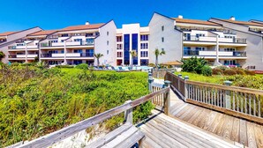 A modern hotel with multiple balconies, a swimming pool, and a wooden deck. - Beautiful 3rd-Floor Oceanfront Condow/Private Balcony & Shared Outdoor Pool (Pine Knoll Shores)