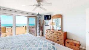 A bedroom with a bed, a dresser, a mirror, and a television. - Beautiful 3rd-Floor Oceanfront Condow/Private Balcony & Shared Outdoor Pool (Pine Knoll Shores)