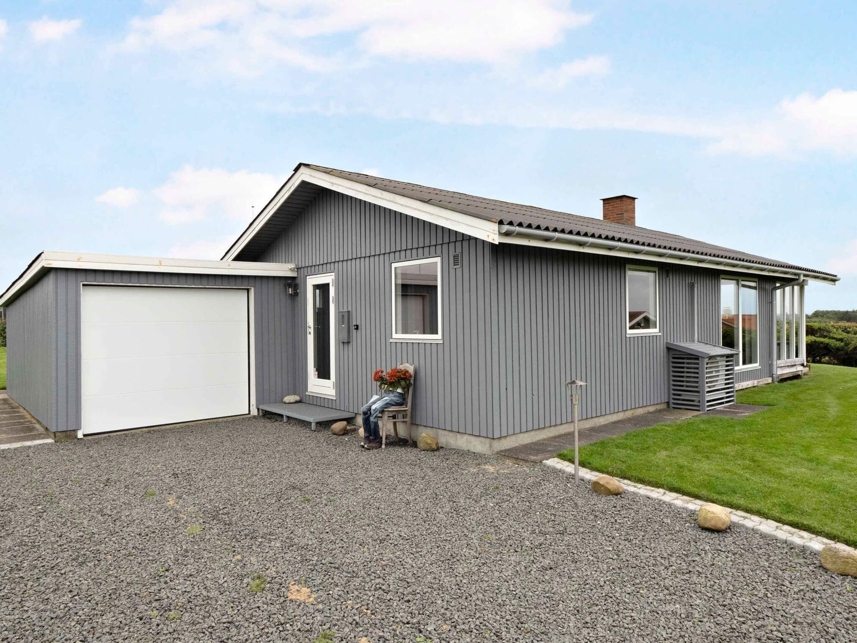 Een modern gelijkvloers huis met garage, een klein portaaltje en een grindpad.