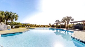 A clear swimming pool with a tiled deck, surrounded by palm trees and a fence. - Wonderful condo with private washer/dryer, balcony, and pool/tennis (Atlantic Beach)
