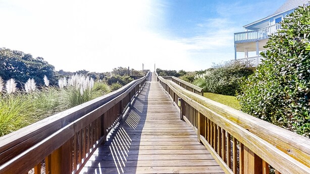 A wooden boardwalk leading to a building with a balcony, surrounded by greenery and tall grasses. - Wonderful condo with private washer/dryer, balcony, and pool/tennis (Atlantic Beach)
