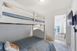 A bunk bed room with a television, a lamp, and a view of the outside. - Updated 3rd-Floor Home With Courtyard & Partial Beach View, Shared Pools/Hot Tub (Atlantic Beach)