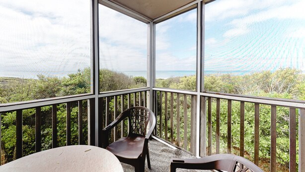 A covered balcony with a view of the sea and greenery. - 2nd Floor in Resort w/Direct Beach Access + Free WiFi, Balcony, Shared Pool (Atlantic Beach)