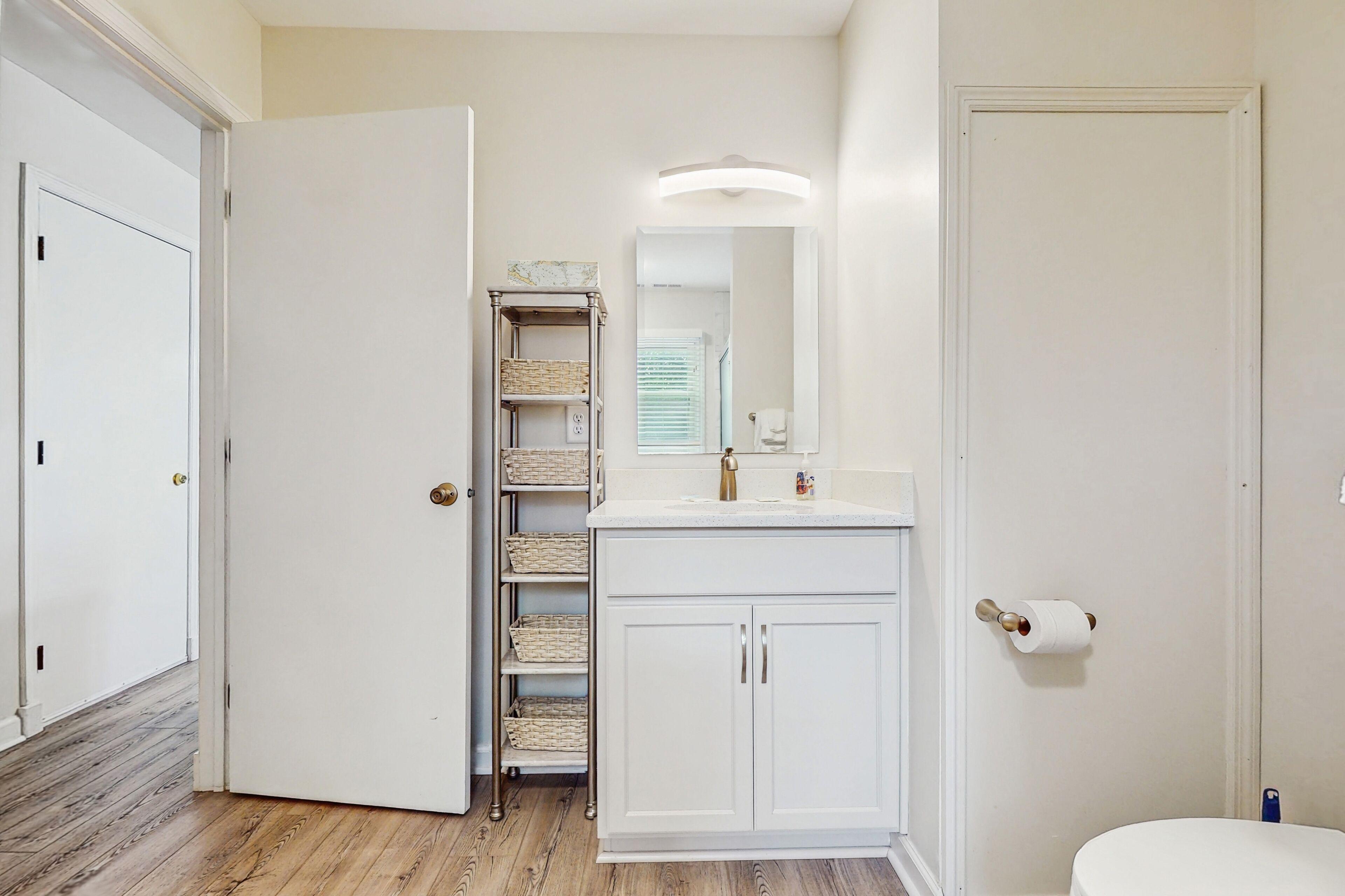 Une salle de bain avec un meuble-lavabo blanc, un miroir et des toilettes.