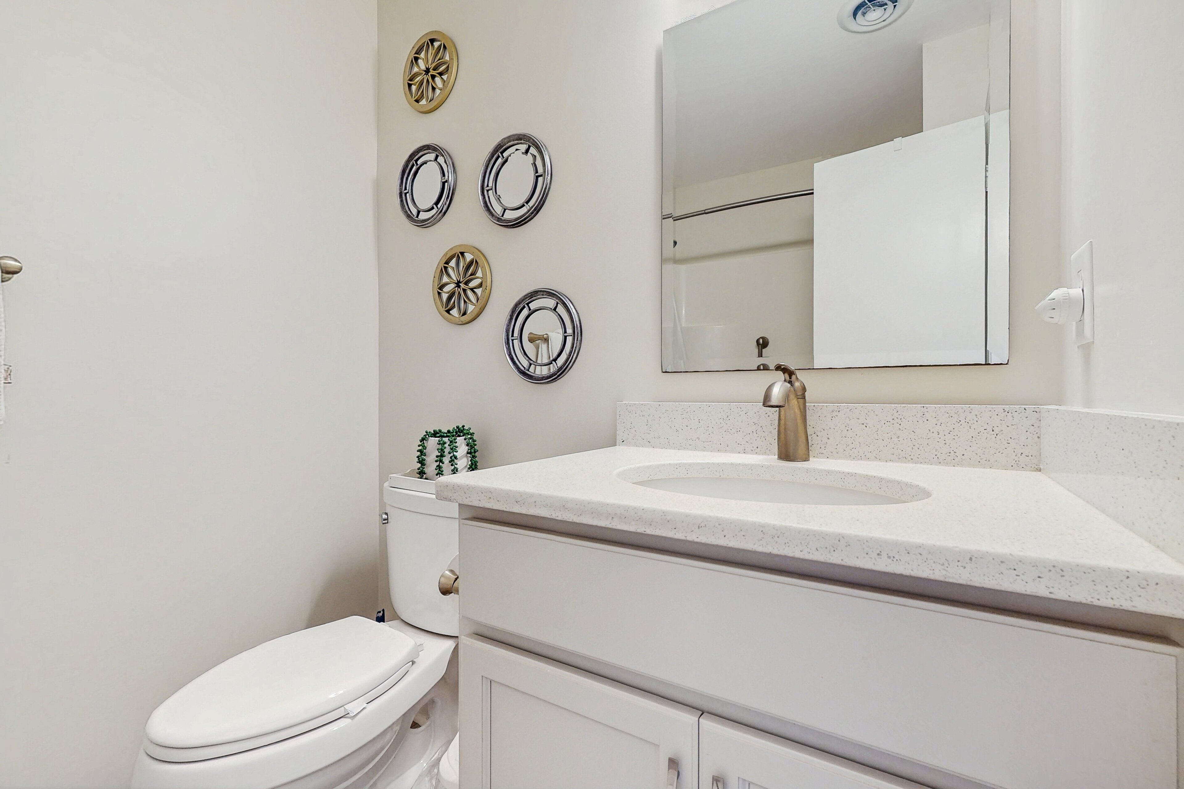 A bathroom with a white toilet, a sink with a mirror above it, and decorative plates on the wall.
