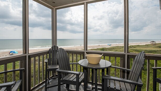 A covered outdoor area with a view of the beach, featuring a table with chairs and a bowl. - Lovely Condo in Direct Oceanfront Complex w/Shared Pool, Free WiFi, Water Views (Atlantic Beach)