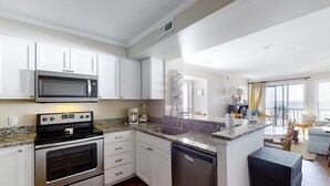A modern kitchen with stainless steel appliances, white cabinetry, and a granite countertop. - Lovely Condo in Direct Oceanfront Complex w/Shared Pool, Free WiFi, Water Views (Atlantic Beach)