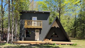 Eine Hütte mit Balkon, Tür und einem kleinen dreieckigen Aufbau.