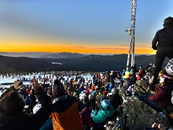A large crowd of people gathered around a tall communication tower, likely for a viewing or event.