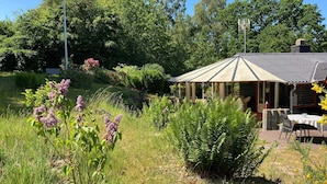 En have med en pavillon, et bord med stole og en bænk.