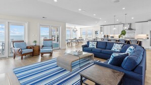A spacious living room with a blue sofa, two armchairs, a coffee table, and a striped rug.