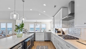 A modern kitchen with white cabinets, stainless steel appliances, and a large island.