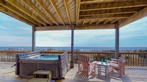 A wooden deck with a hot tub, chairs, and a table overlooking the beach. - Oceanfront, Dog-Friendly, 4-Bedroom w/ Private Hot Tub, Ocean View, AC, WiFi (Avon)