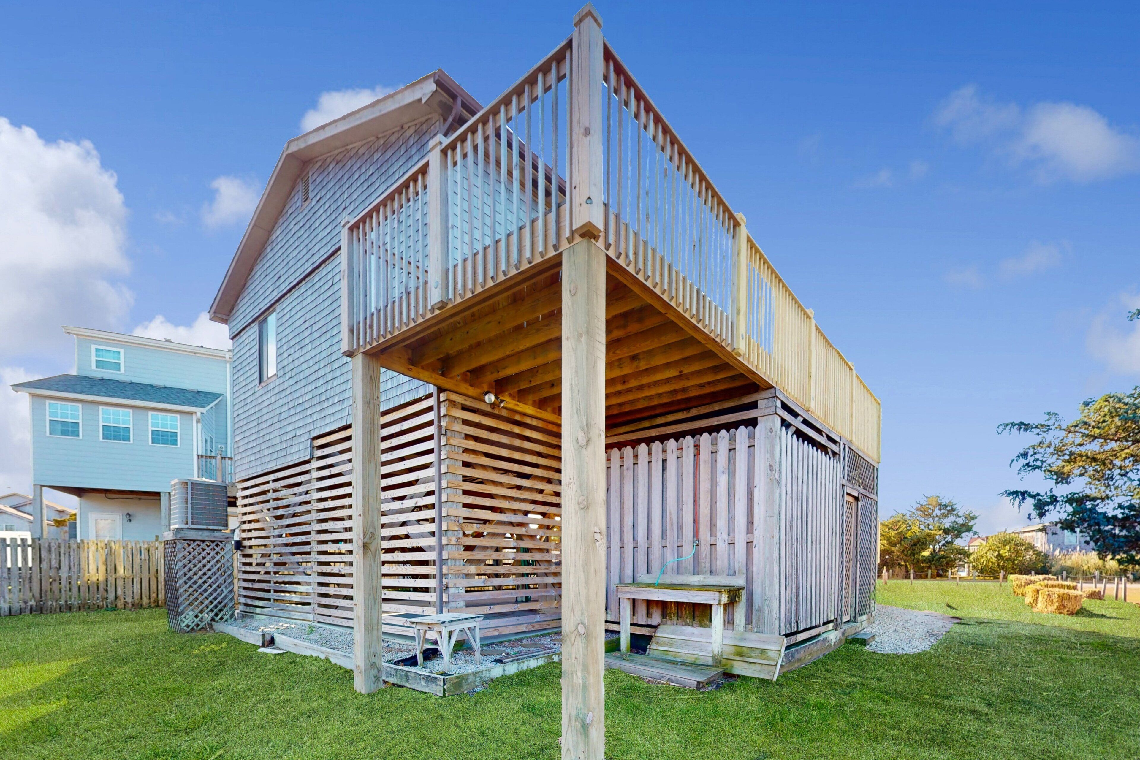 Une maison à deux étages avec une terrasse en bois et une cour arrière clôturée.