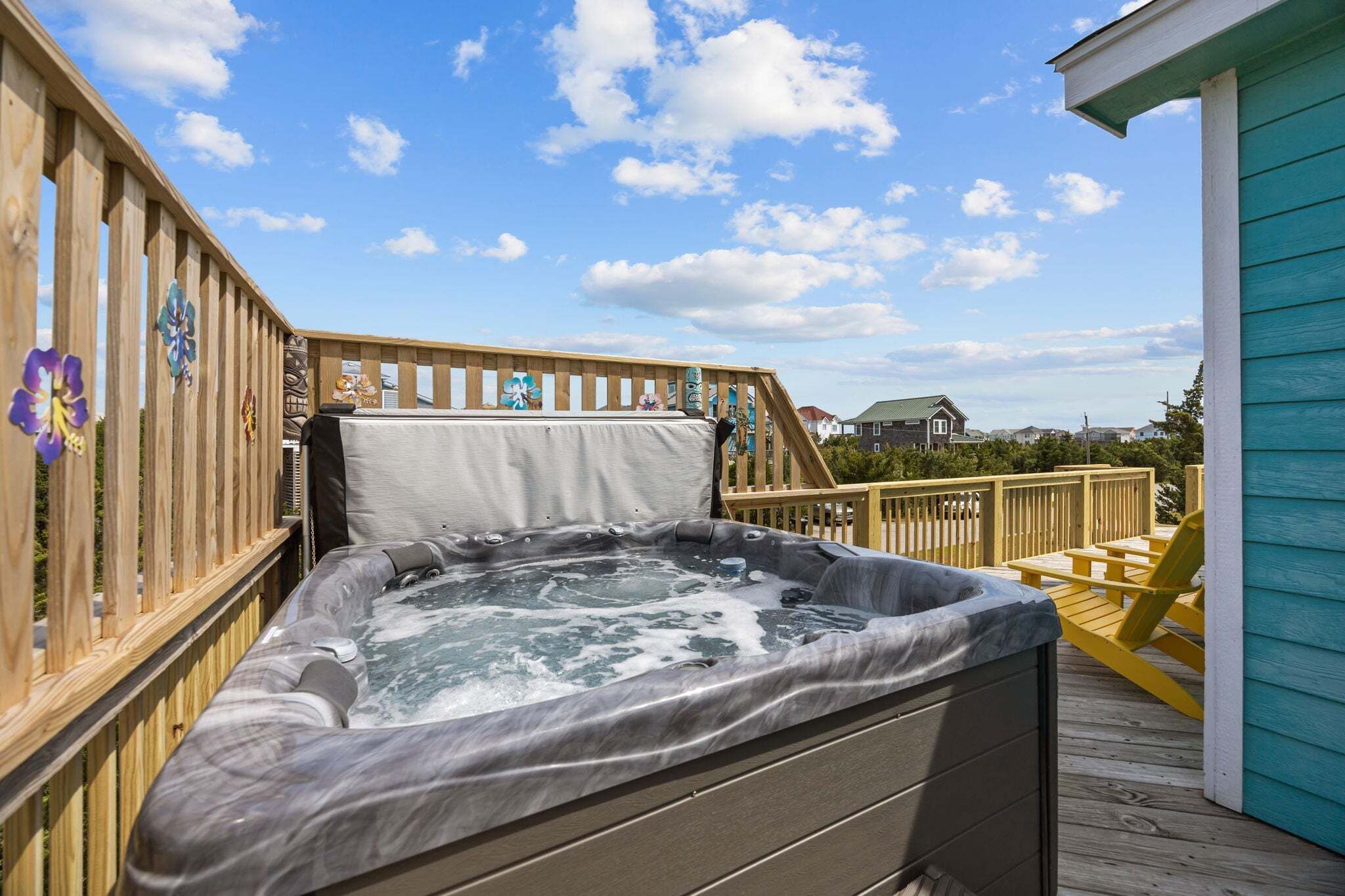 A hot tub on a wooden deck with a view of houses in the background.
