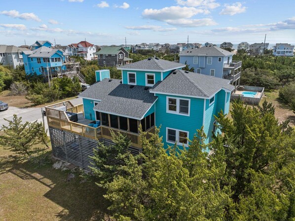 A residential property with a large deck, multiple windows, and a swimming pool.