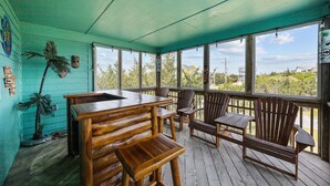 Una terraza de madera con una mesa y sillas, rodeada de amplios ventanales.