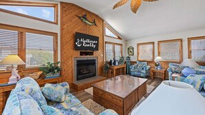 Una sala de estar acogedora con chimenea, paredes de madera y mobiliario azul con estampado.
