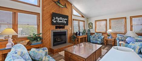 A cozy living room with a fireplace, wooden walls, and blue patterned furniture.