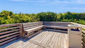 Una terraza de madera con bancos y un contenedor de basura.