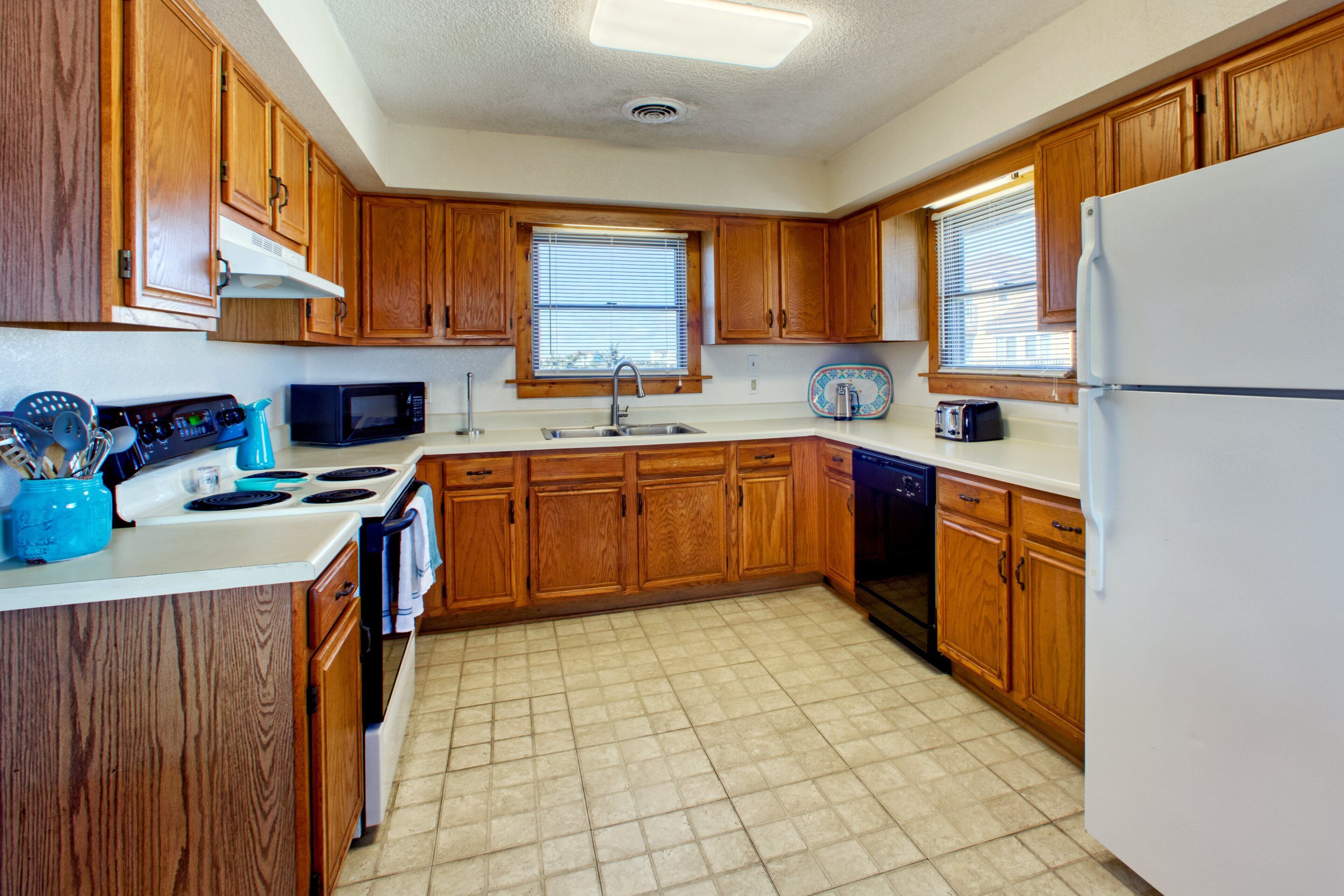 A kitchen with wooden cabinets, a white refrigerator, a microwave, a stove, and a dishwasher.