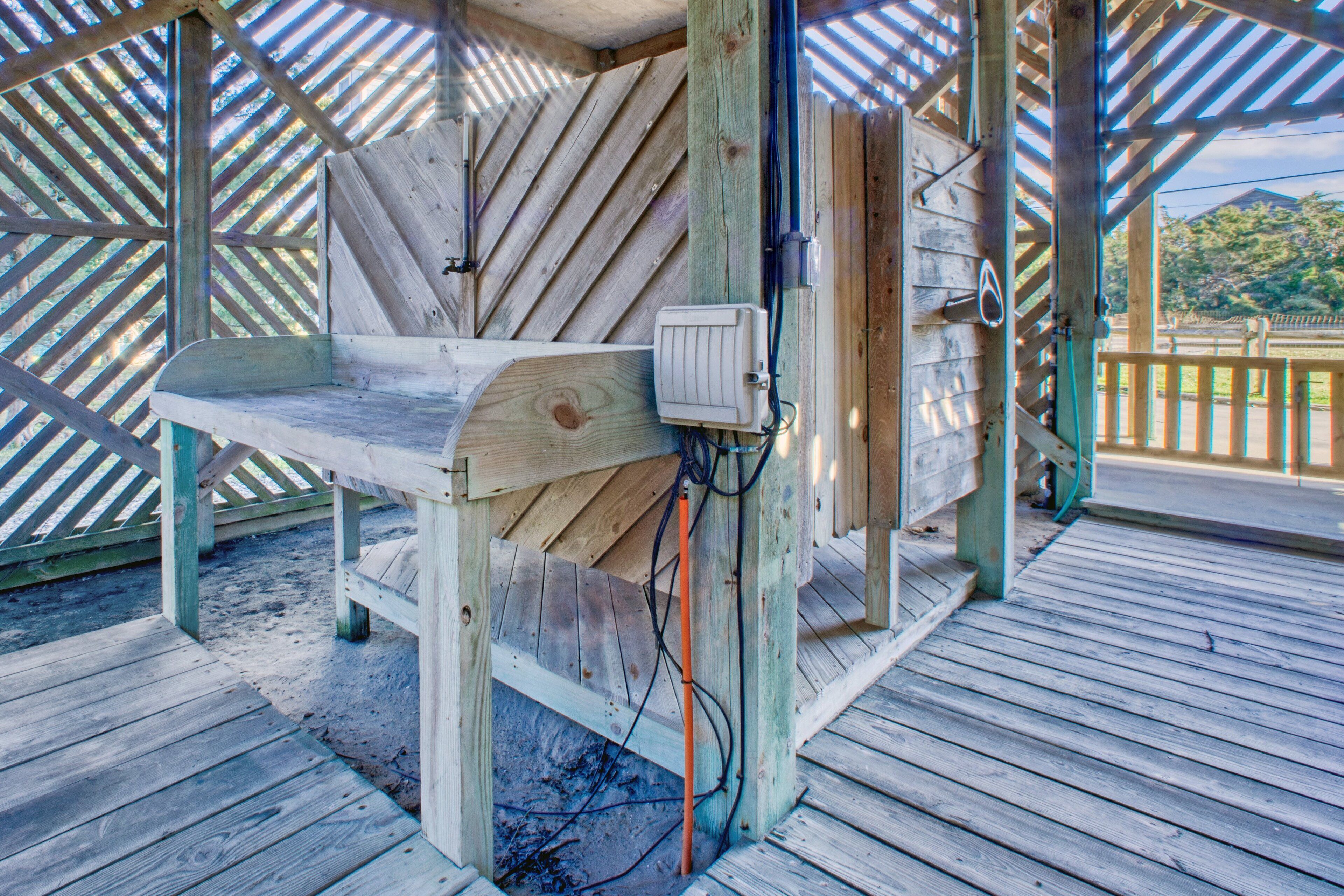 Un banc en bois placé sous une structure également en bois, agrémenté d’une rambarde en métal et doté d’un plancher en bois.
