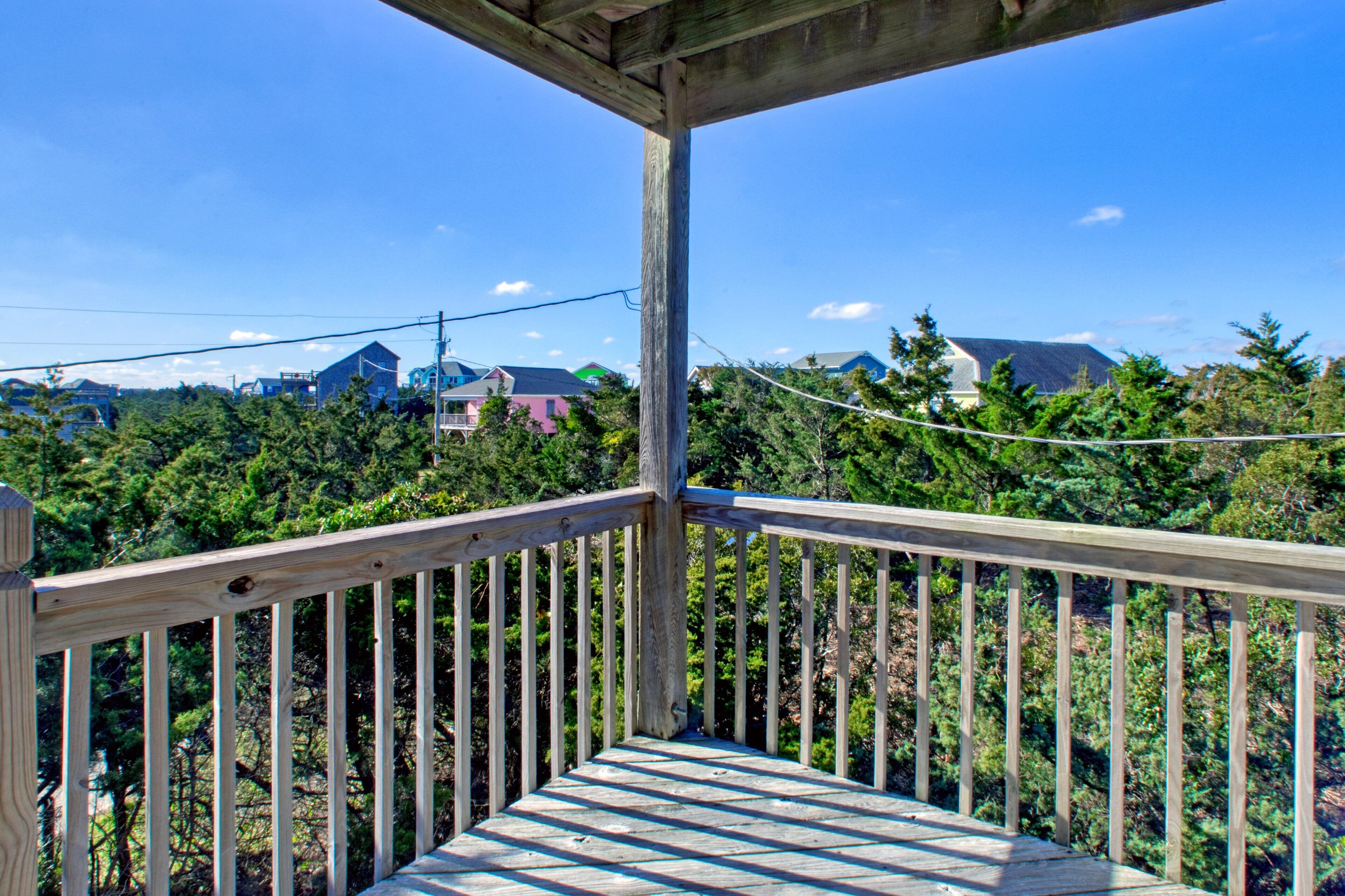 Una terraza de madera con vistas a un bosque y casas al fondo.