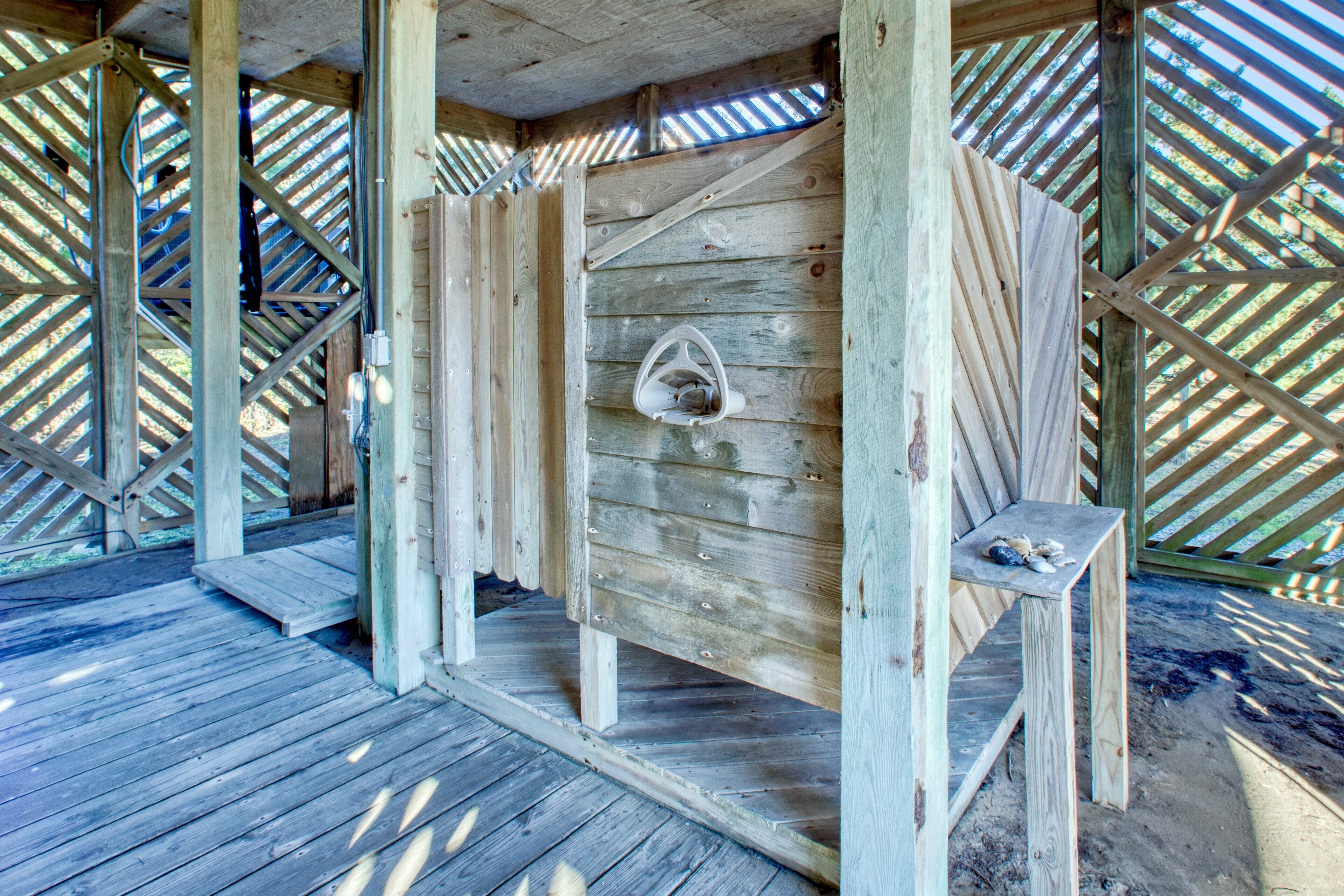A wooden cabin with a sloped roof, a bench, and a hanging light fixture.