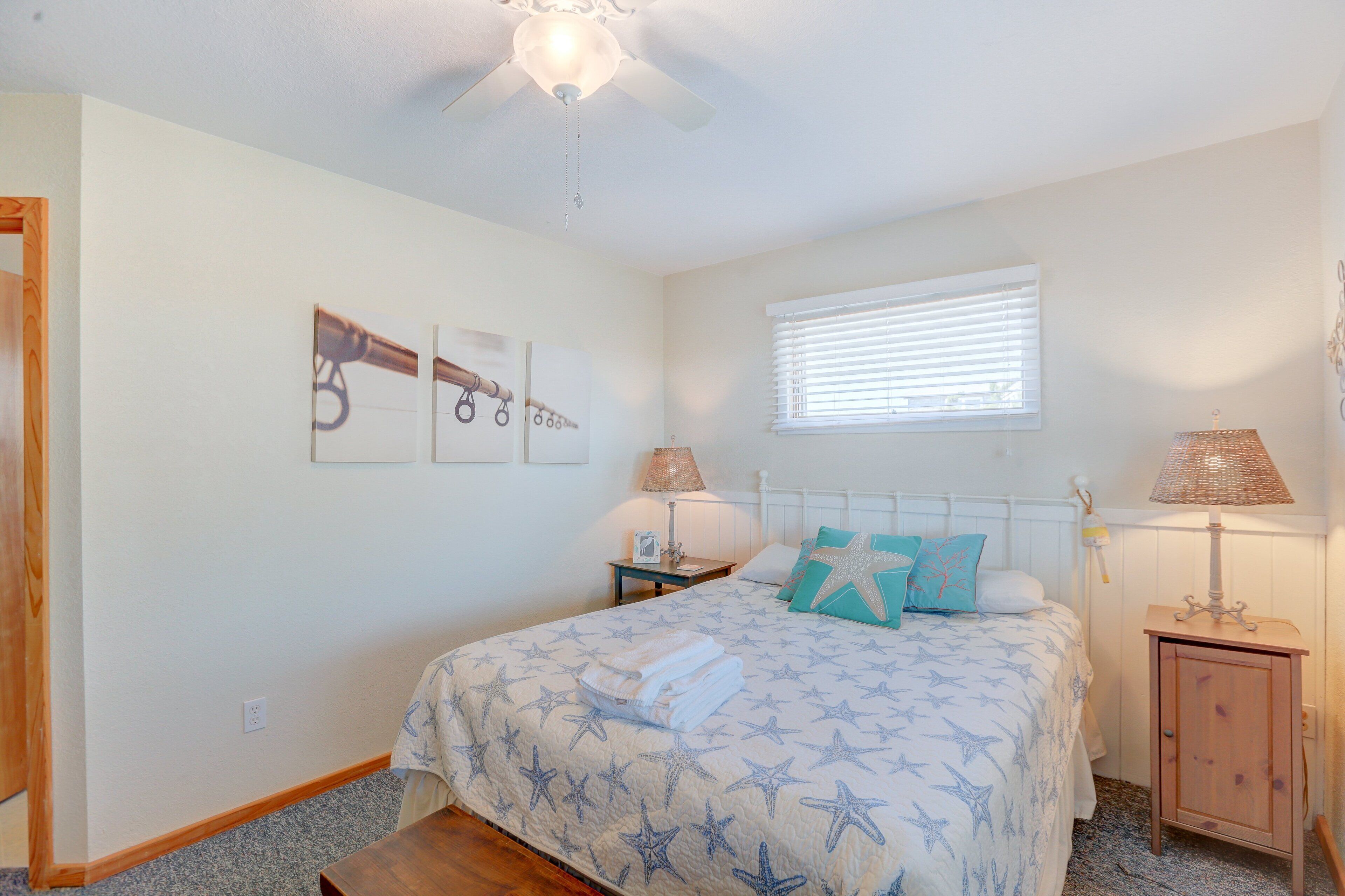 A bedroom with a bed, a nightstand, a window with blinds, and a ceiling fan.