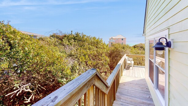 A wooden deck leading to a building with a window and a lantern.