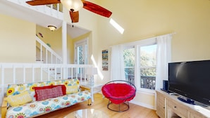 A living room with a sofa, red chair, TV, and a staircase.