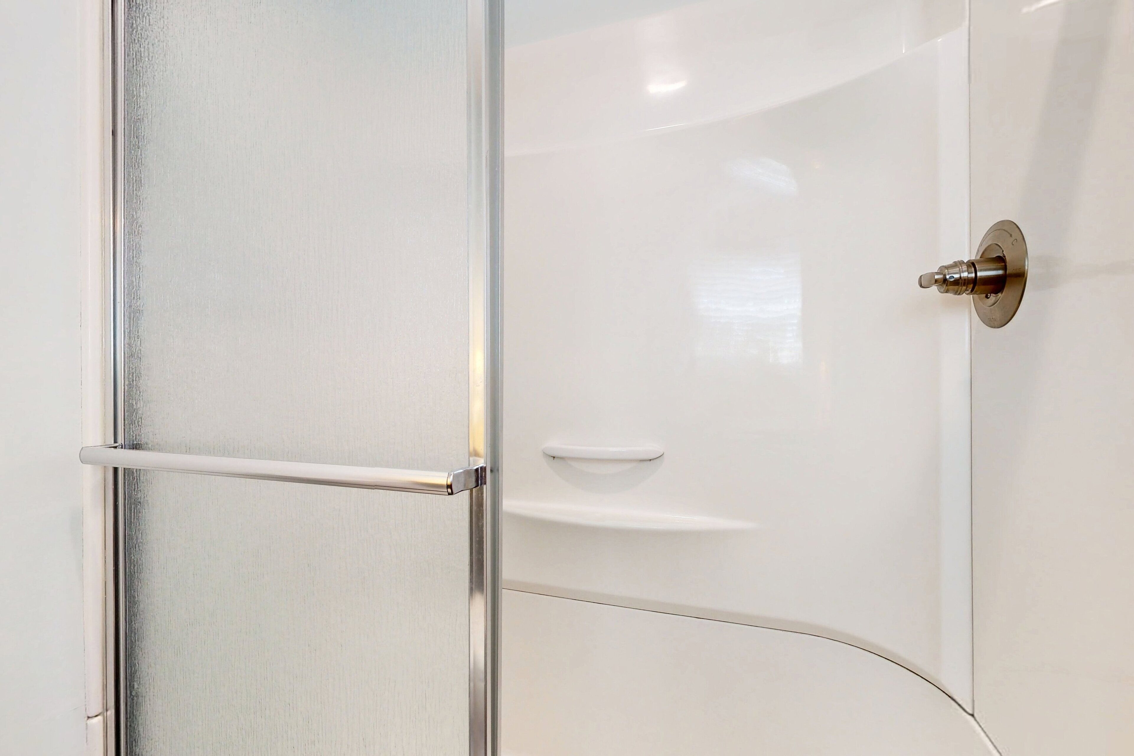 Une salle de bain avec une porte blanche, une poignée en chrome et une barre à serviettes en chrome.