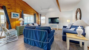 A cozy living room with a blue sofa, a rocking chair, and a television. - Waterfront Home on Bulk-Headed Lot w/ Private Hot Tub, Sound View, Shared Pool (Avon)