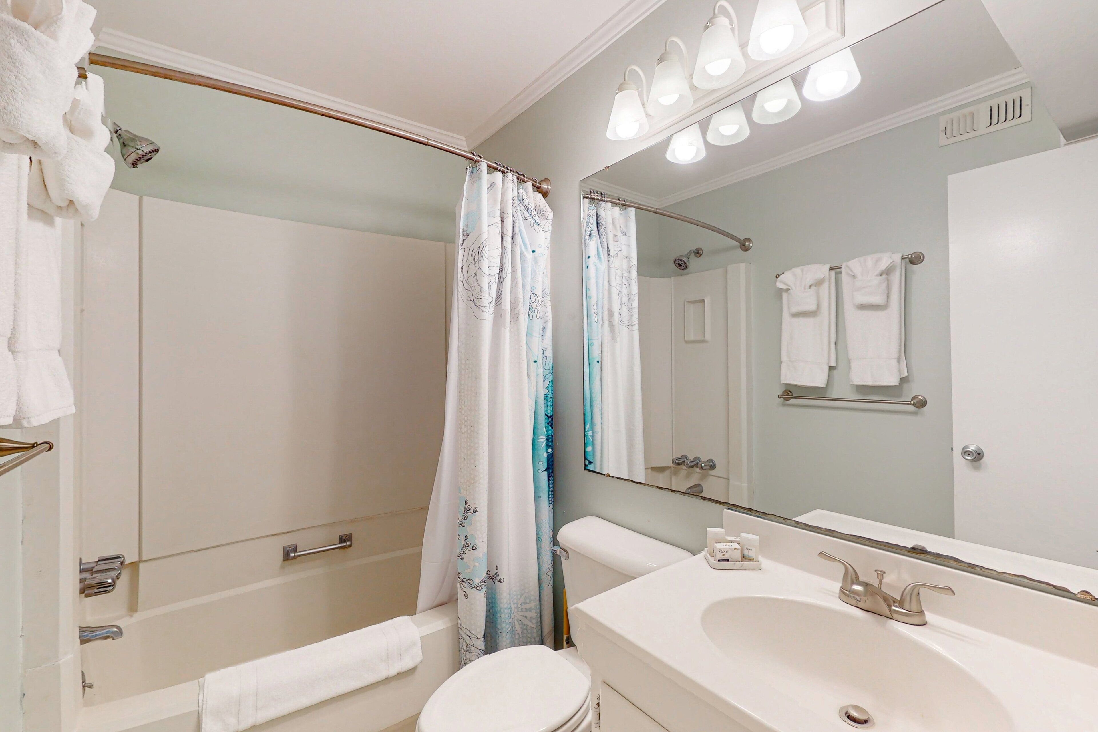 A bathroom with a bathtub, toilet, sink, and a large mirror.