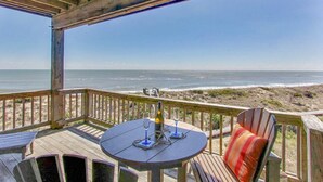 Une terrasse en bois avec une table et des chaises, donnant sur une plage.
