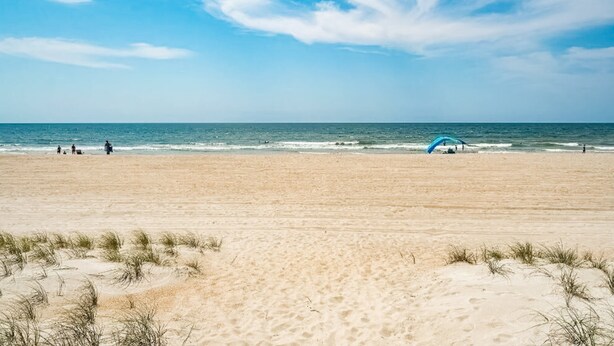 A sandy beach with a clear sky and gentle waves. - Sea Alcove: Colorful studio near the ocean with pool & kitchenette (Atlantic Beach)