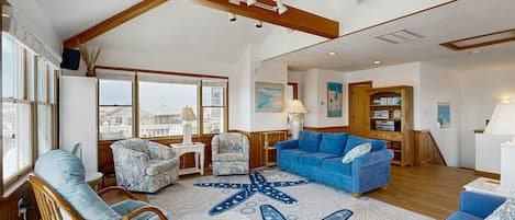 A spacious living room with a large starfish rug, a blue sofa, and a wicker chair.