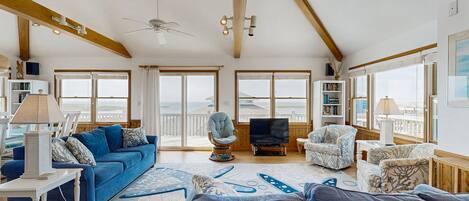 Un salon spacieux avec un plafond haut, de grandes fenêtres et une vue sur la mer.
