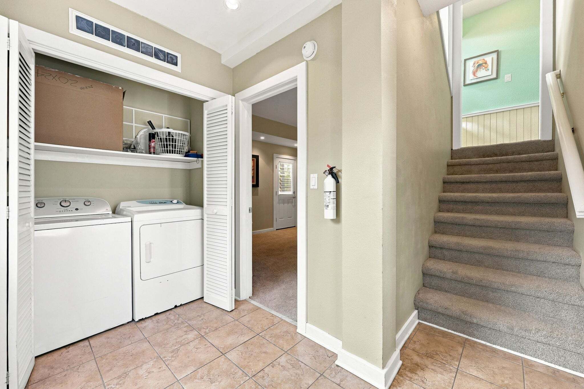A laundry area with a washing machine, dryer, and a utility room with a fire extinguisher.