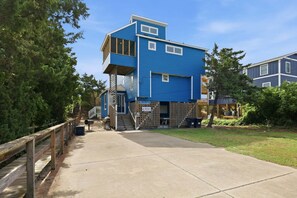 Un bâtiment à deux étages, à la façade bleue, doté d’une terrasse en bois et d’une enseigne indiquant le nom d’une entreprise.