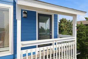 A residential building with a blue exterior, a white porch, and a glass door.