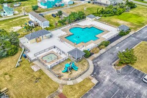 Vista aérea de una zona residencial con piscina, parque infantil y aparcamiento.