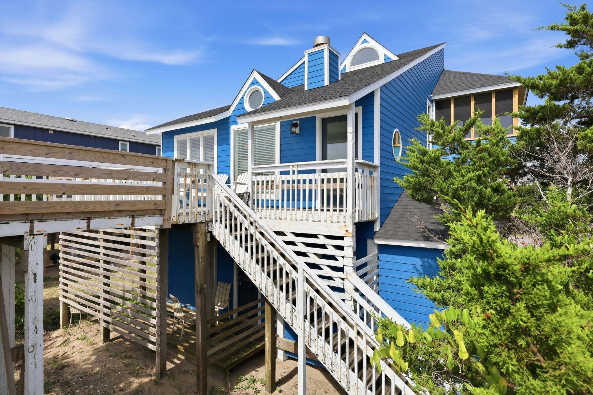 A two-story building with a wooden deck and stairs leading to a balcony.