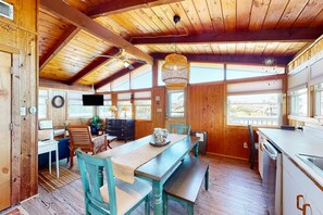 Un intérieur en bois comprenant une table à manger, des bancs et un coin cuisine.