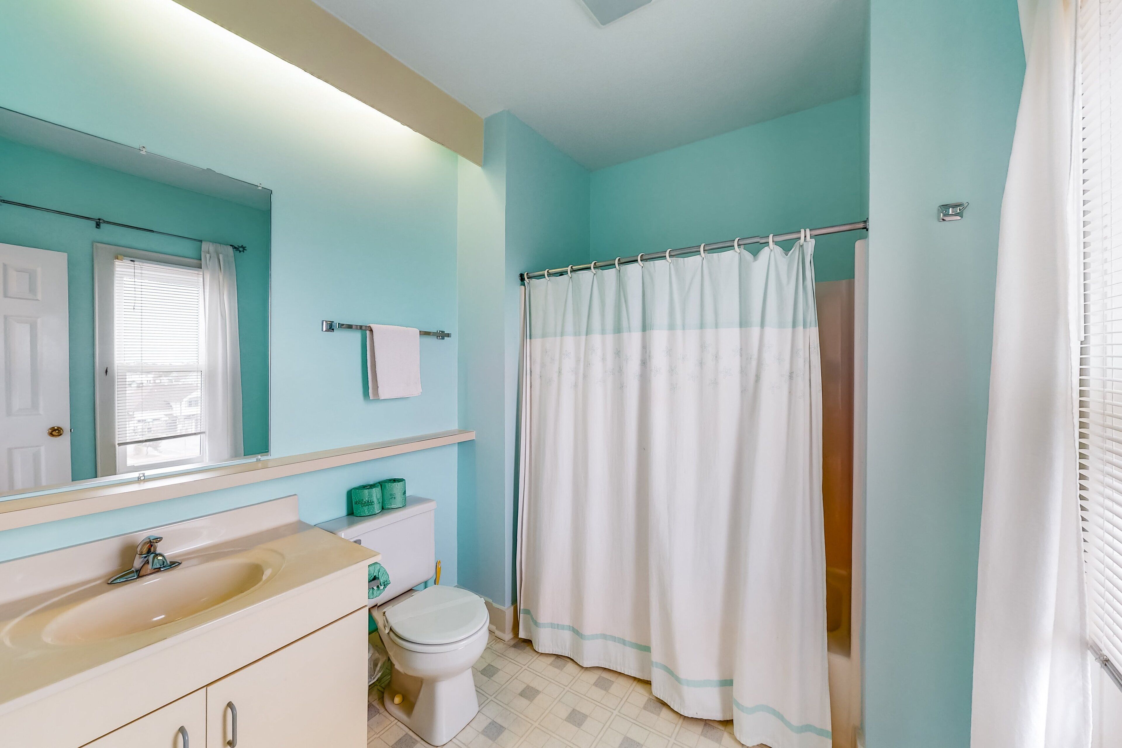A bathroom with a sink, toilet, and shower curtain.