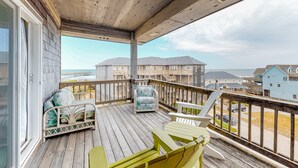 A wooden deck with outdoor furniture, a view of residential buildings, and a clear sky. - FKA Kimogener Point - ocean views, WiFi, W/D, balcony, pool & beach access (Avon)