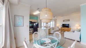 A modern living room with a dining area, kitchen, and a TV in the background. - FKA Kimogener Point - ocean views, WiFi, W/D, balcony, pool & beach access (Avon)