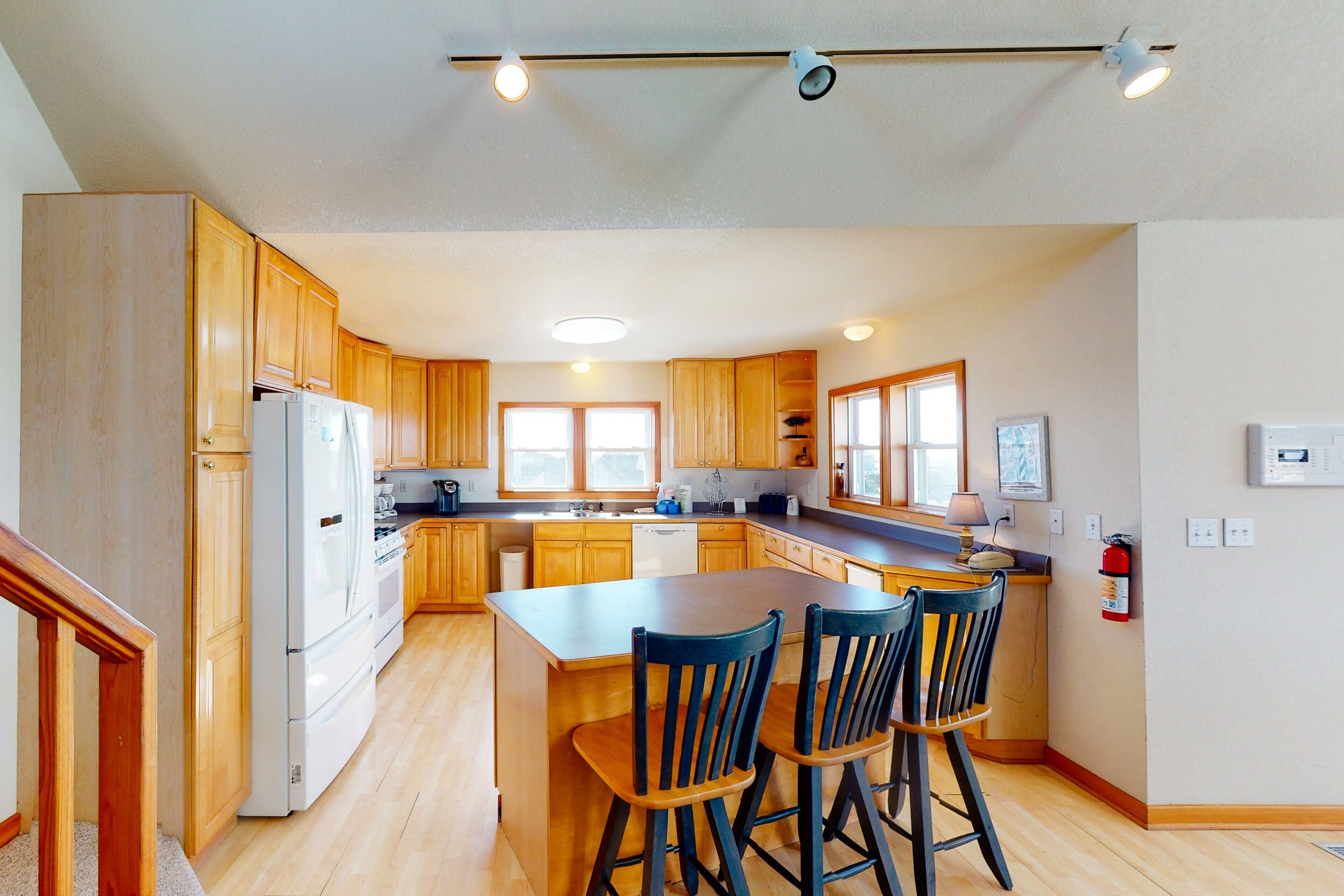 Une cuisine moderne avec des meubles en bois, un îlot central doté de tabourets et des appareils électroménagers intégrés.